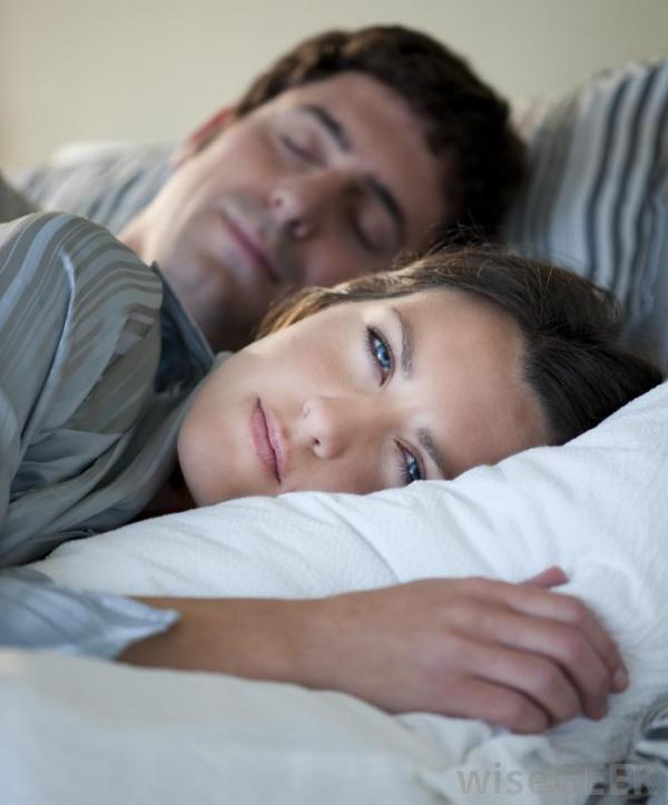 woman-experiencing-insomnia-near-sleeping-man